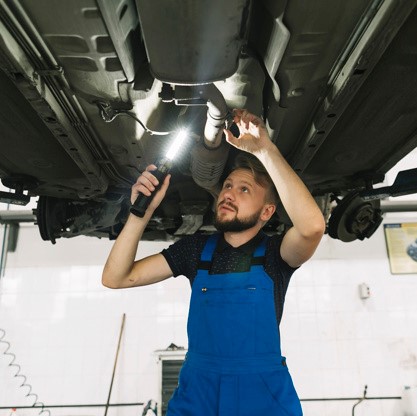repairmen-inspecting-bottom-car-with-lamp_23-2147897945